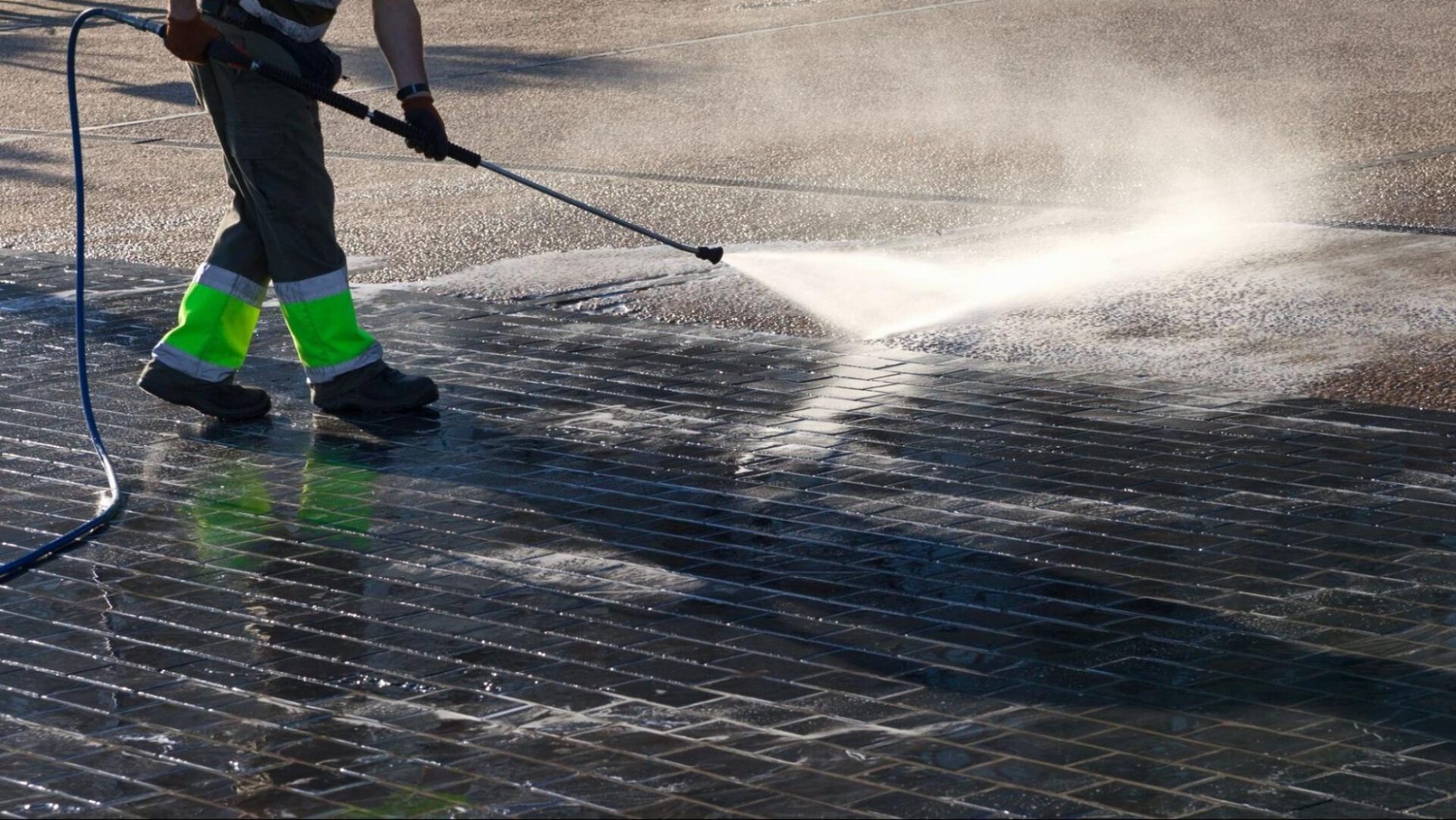 Driveway & Sidewalk Cleaning Person pressure washing a cobblestone surface.